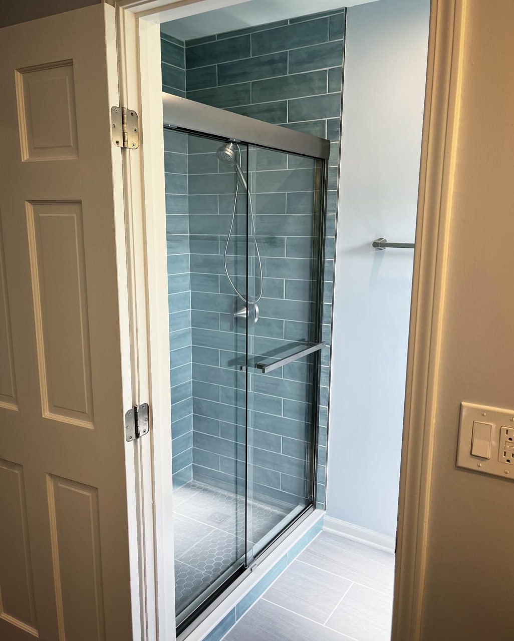 Walk-in glass shower with blue tile installed by ReDesignFix