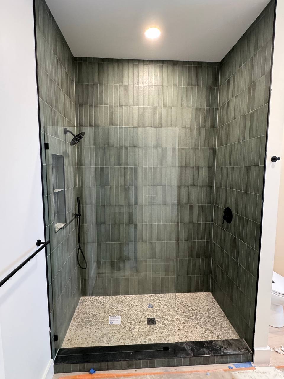 Walk-in glass shower with green tile